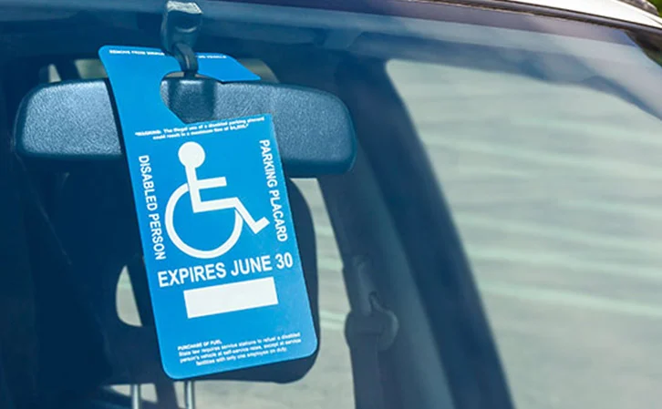 Blue disability parking placard hanging from a vehicle rearview mirror
